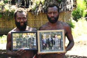 Dos miembros de una tribu en Yaohnanen muestran fotos enmarcadas de su visita en 2007 con el Príncipe Felipe de Edimburgo, su dios