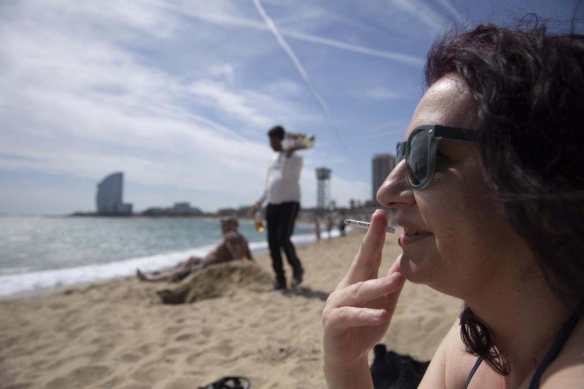 Una mujer fumando en una playa de Barcelona.