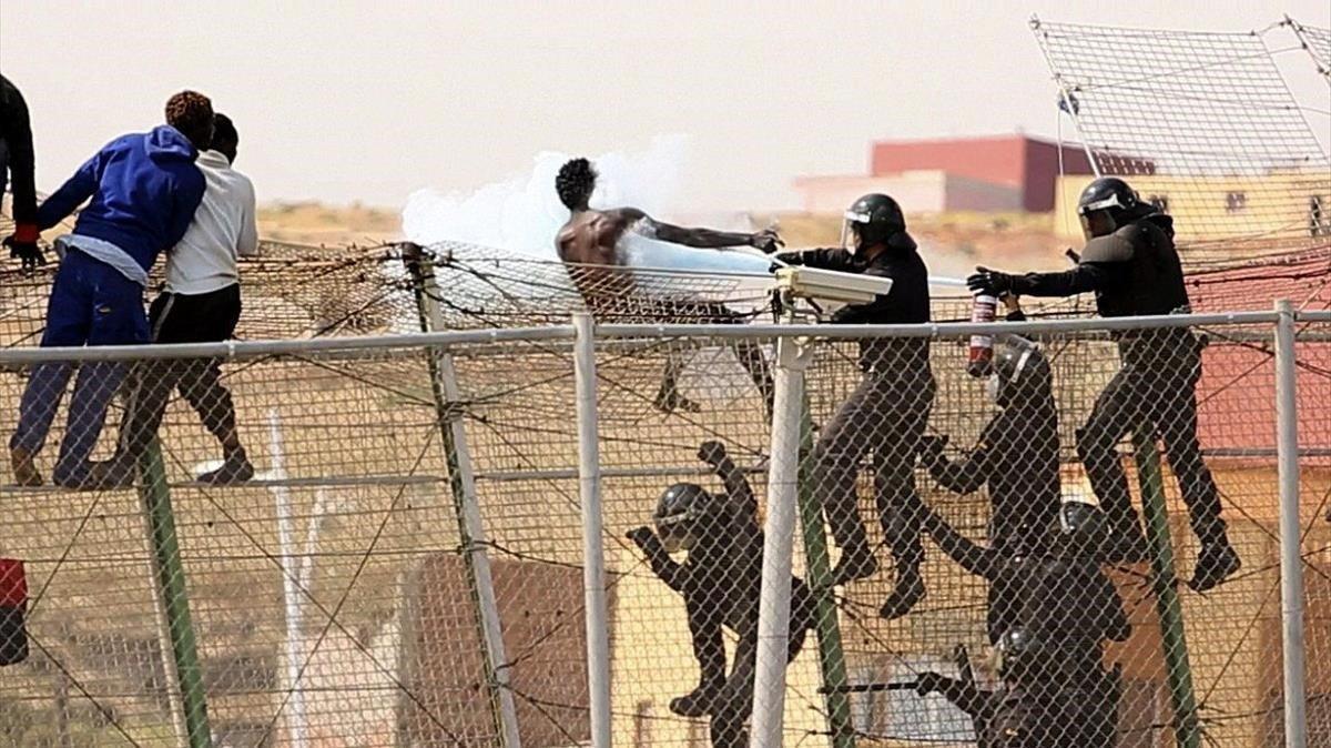 Guardias civiles rocían con un extintor a inmigrantes que intentaban usar mecheros en la valla de Melilla en una operación anterior. Guardias civiles rocían con un extintor a inmigrantes que intentaban usar mecheros en la valla de Melilla en una operación anterior.