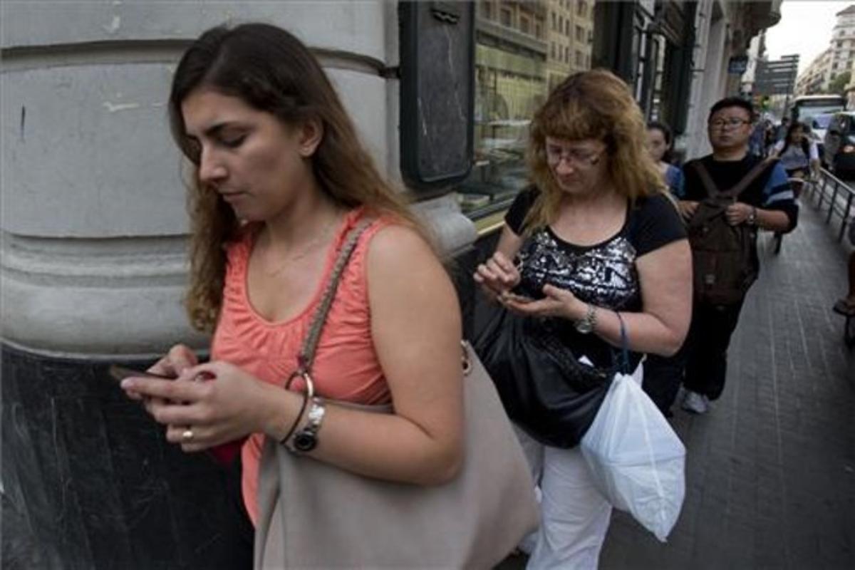 Usuarios de ’smartphones’ chateando mientras caminan.