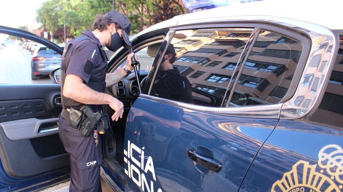 Un agente de la Policía Nacional, junto a su coche patrulla. Un agente de la Policía Nacional, junto a su coche patrulla.