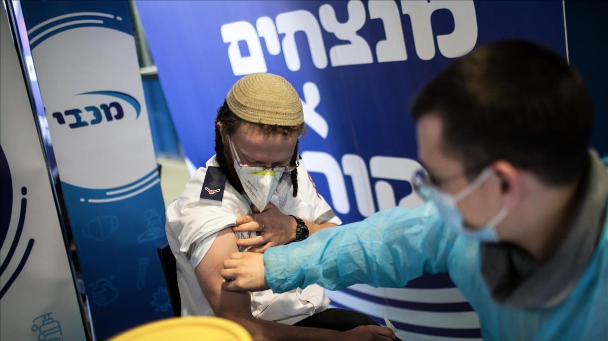 Un sanitario pone la vacuna a un hombre en un centro de vacunación en Jerusalén.
