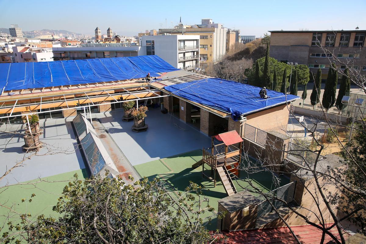 La lona desplegada en el tejado de la escuela Muntanyeta, en Barcelona, tras sufrir un robo y desprenderse parte del techo. 