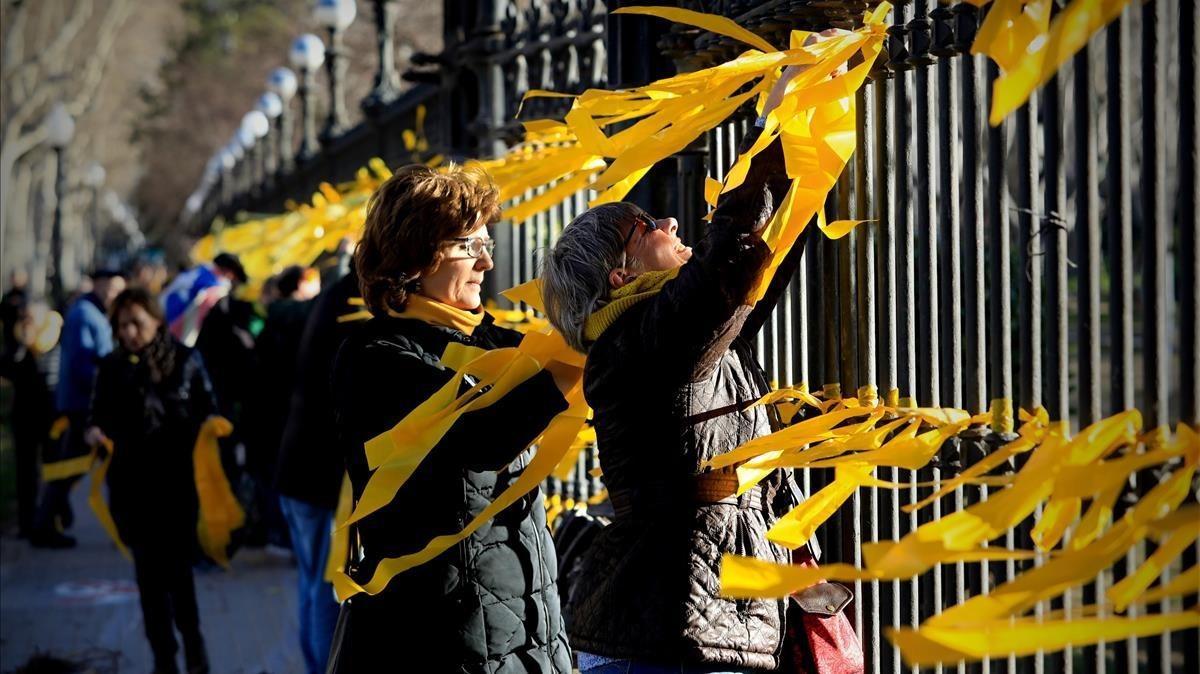 Varias personas colocan lazos amarillos en el parque de la Ciutadella de Barcelona