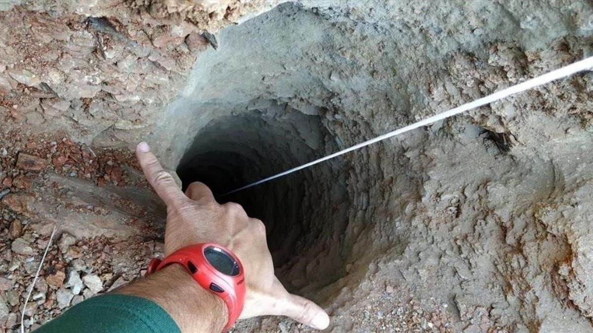 Un guardia civil señala el orificio de apenas 30 centímetros de ancho del pozo. Un guardia civil señala el orificio de apenas 30 centímetros de ancho del pozo.