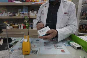 Un farmacéutico recorta el código de barras de una caja de paracetamol en su farmacia de Madrid.