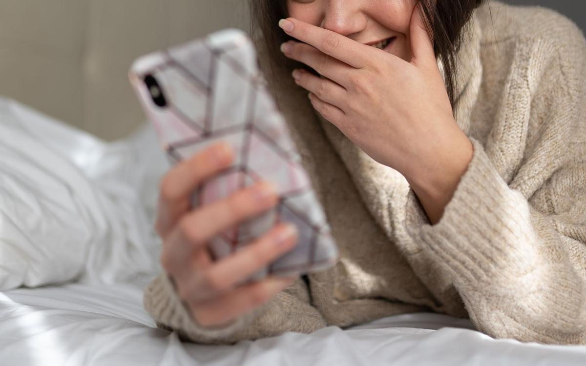 Una joven se ríe mientras usa su teléfono móvil Una joven se ríe mientras usa su teléfono móvil