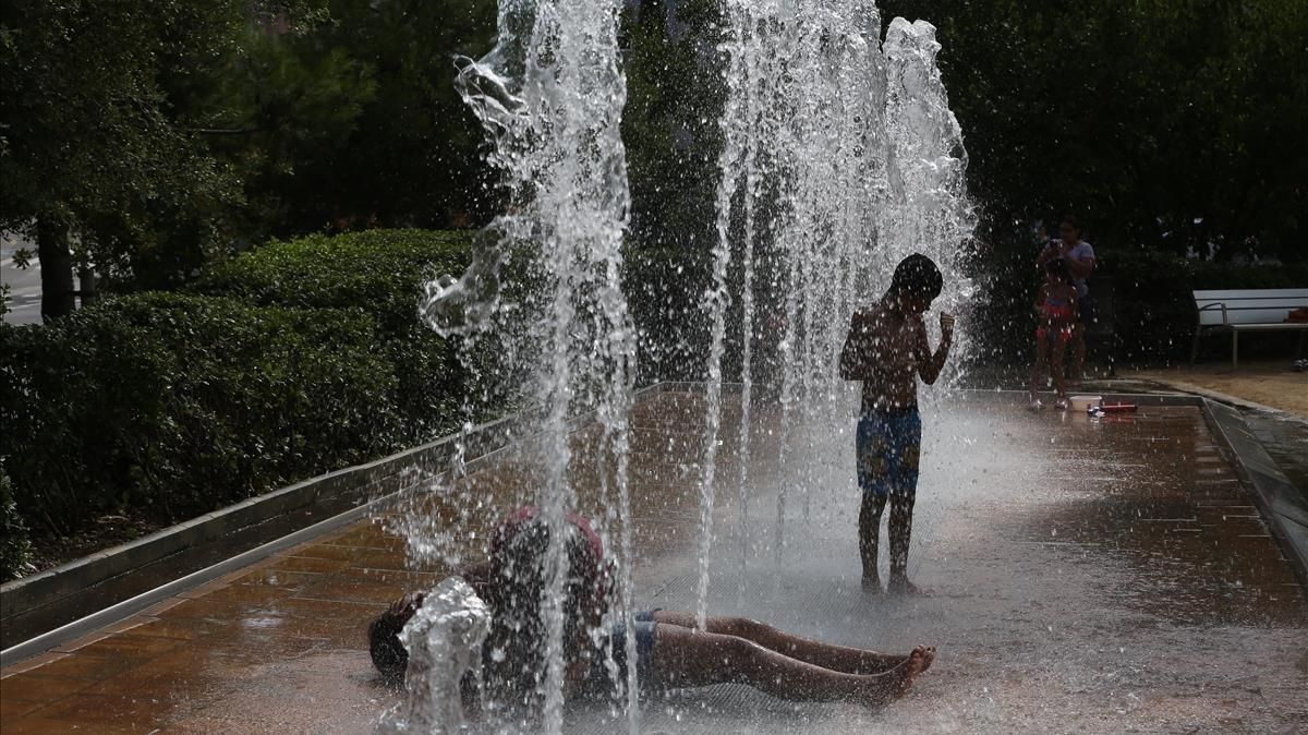 Unos barceloneses se refrescan en las fuentes de la avenida del Estatut. Unos barceloneses se refrescan en las fuentes de la avenida del Estatut.