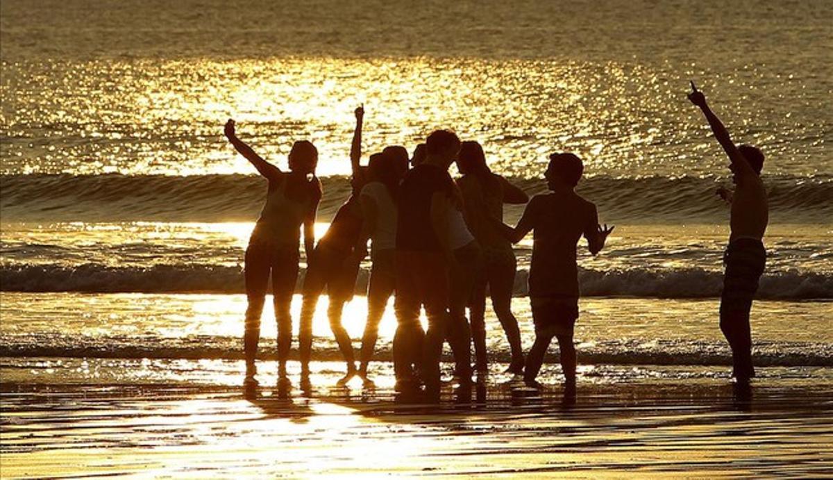 Un grupo de jóvenes disfruta del atardecer en la playa de La Concha de San Sebastián.