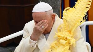 El Papa Francisco, sosteniendo una rama de palma tejida, reacciona mientras se sienta en el auto papamóvil durante la misa del Domingo de Ramos en la plaza de San Pedro el 2 de abril de 2023 en el Vaticano.