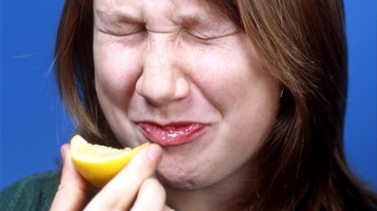 Una chica muerde un limón.