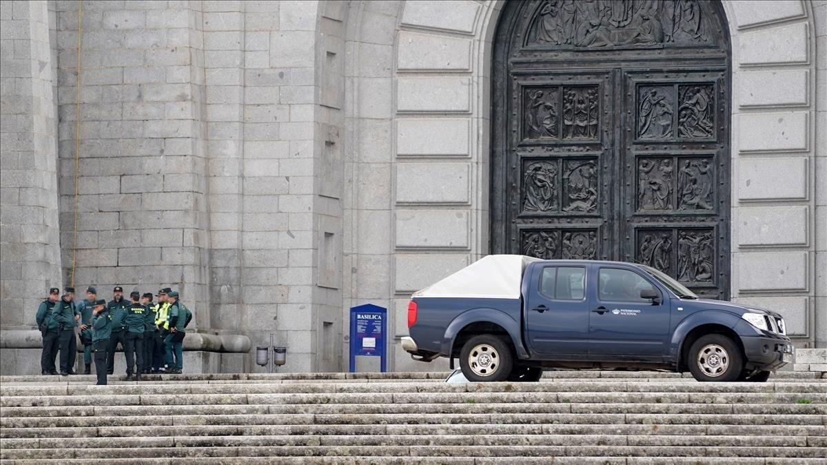 Un grupo de guardias civiles de los que han realizado preparativos esta mañana en la basílica del Valle de los Caídos, habla a la puerta de la basílica de la Santa Cruz junto a un coche de operarios de Patrimonio Nacional.