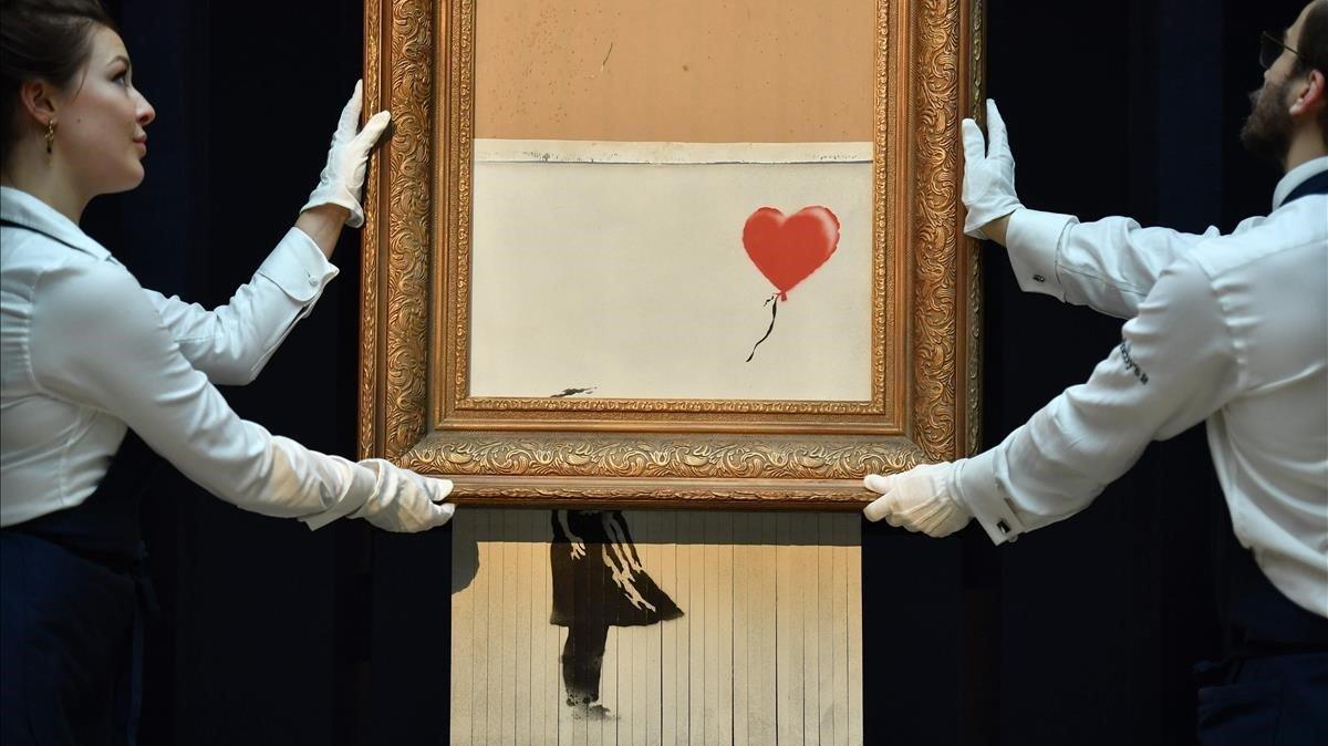 Empleados de Sotheby’s muestran ’Love is in the bin’ de Banksy, la nueva pieza resultado de la autodestrucción, en plena subasta, de ’Girl with a balloon’. Empleados de Sotheby’s muestran ’Love is in the bin’ de Banksy, la nueva pieza resultado de la autodestrucción, en plena subasta, de ’Girl with a balloon’.