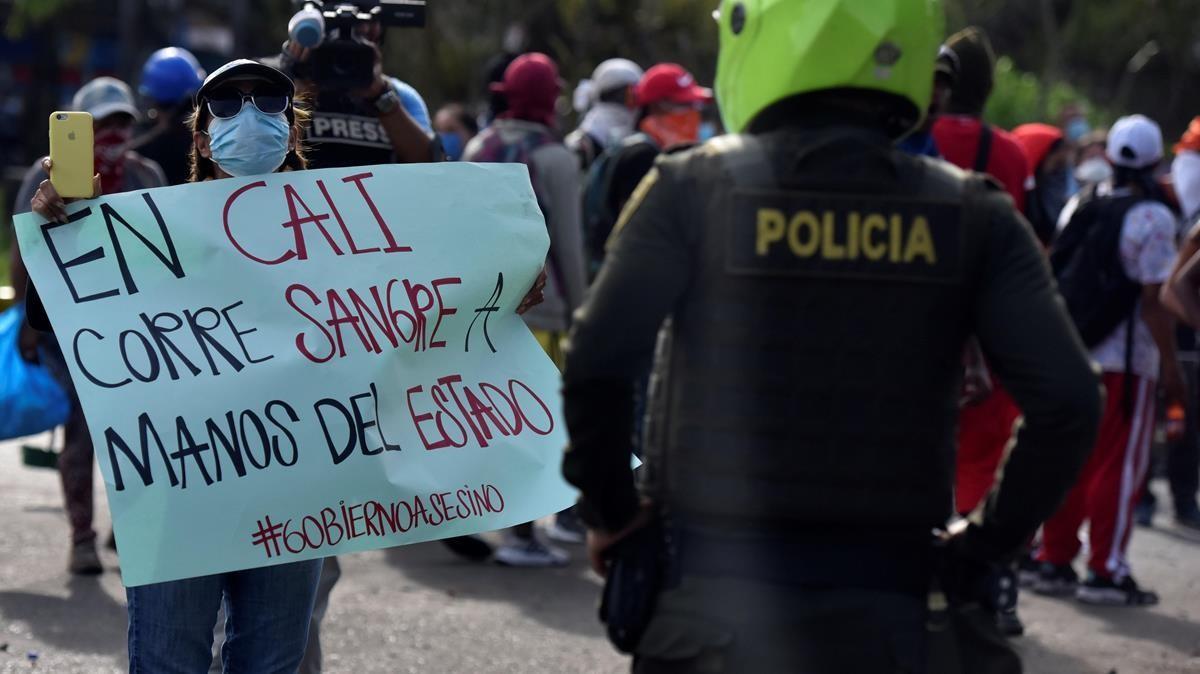 Una manifestante muestra un cartel a un policia durante una de las protestas del martes pasado en el barrio Siloe de la localidad colombiana de Cali.