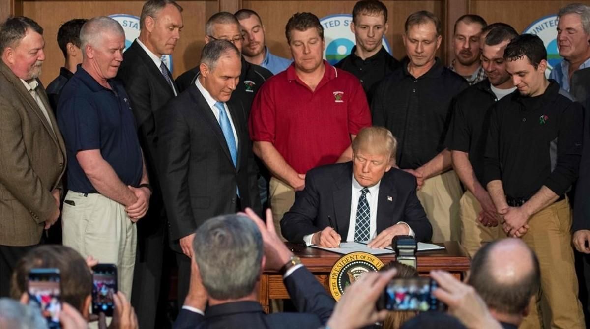 Trump, rodeado de mineros, firma la orden ejecutiva que pone los cimientos para deshacer la política medioambiental de Obama. Trump, rodeado de mineros, firma la orden ejecutiva que pone los cimientos para deshacer la política medioambiental de Obama.