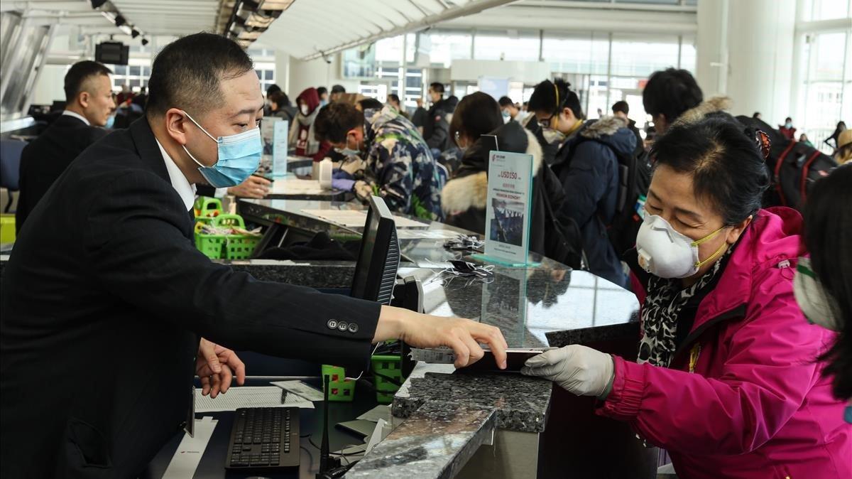 Pasajeros y personal en un aeropueto protegidos con mascarillas por el coronavirus. Pasajeros y personal en un aeropueto protegidos con mascarillas por el coronavirus.