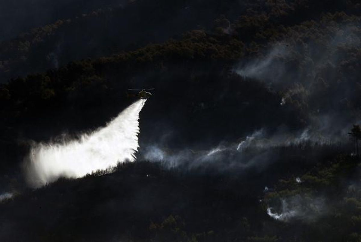 Un helicóptero vierte agua sobre el fuego de Vallirana. Un helicóptero vierte agua sobre el fuego de Vallirana.