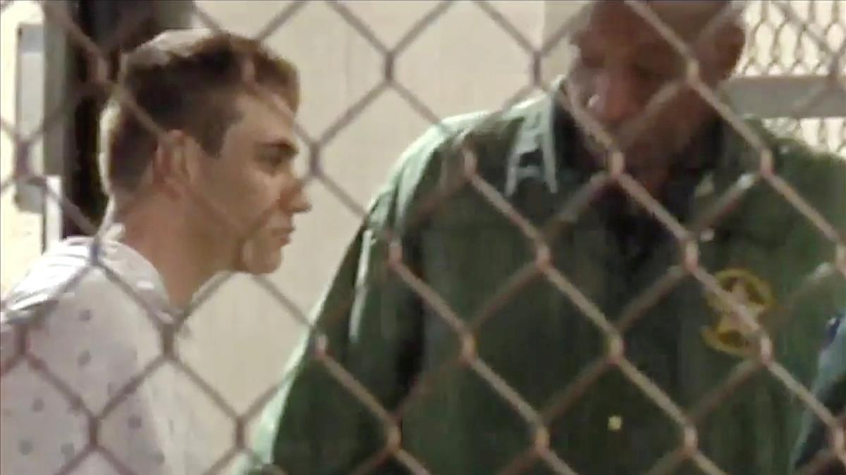 Un policía escolta a Nikolas Cruz (en una imagen de vídeo) en la cárcel del condado de Broward, tras el tiroteo en el instituto de Parkland (Florida), el 15 de febrero.