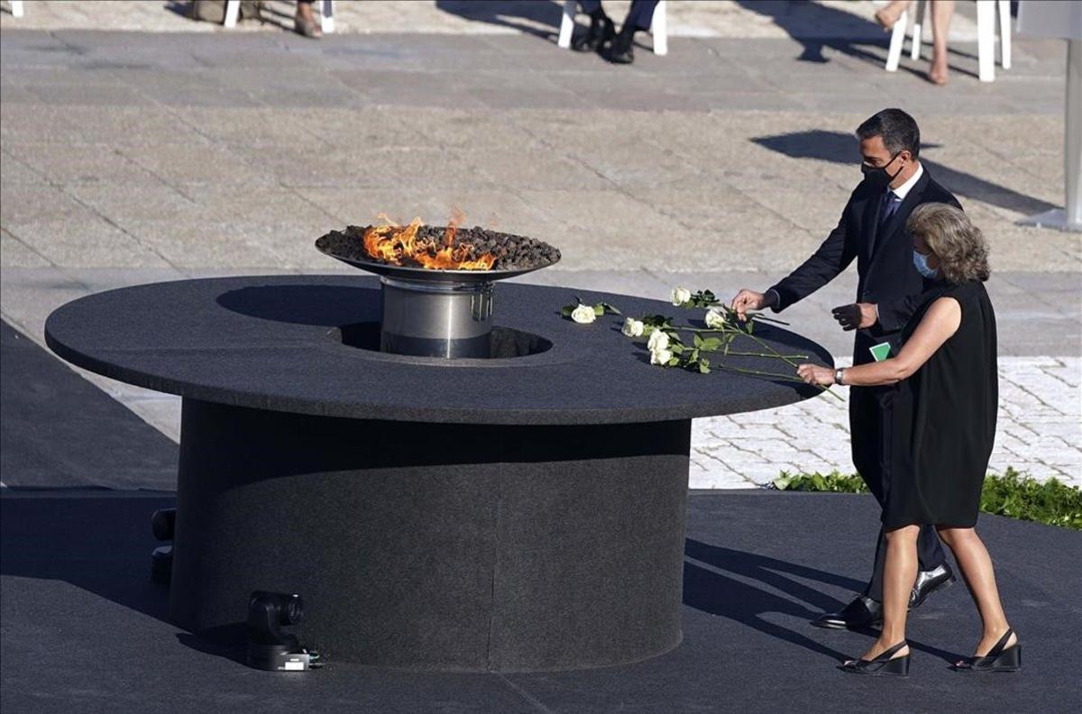 Pedro Sánchez y una participante en el acto dejan una rosa cerca del pebetero, durante el homenaje a las víctimas del covid, esta mañana en Madrid. Pedro Sánchez y una participante en el acto dejan una rosa cerca del pebetero, durante el homenaje a las víctimas del covid, esta mañana en Madrid.