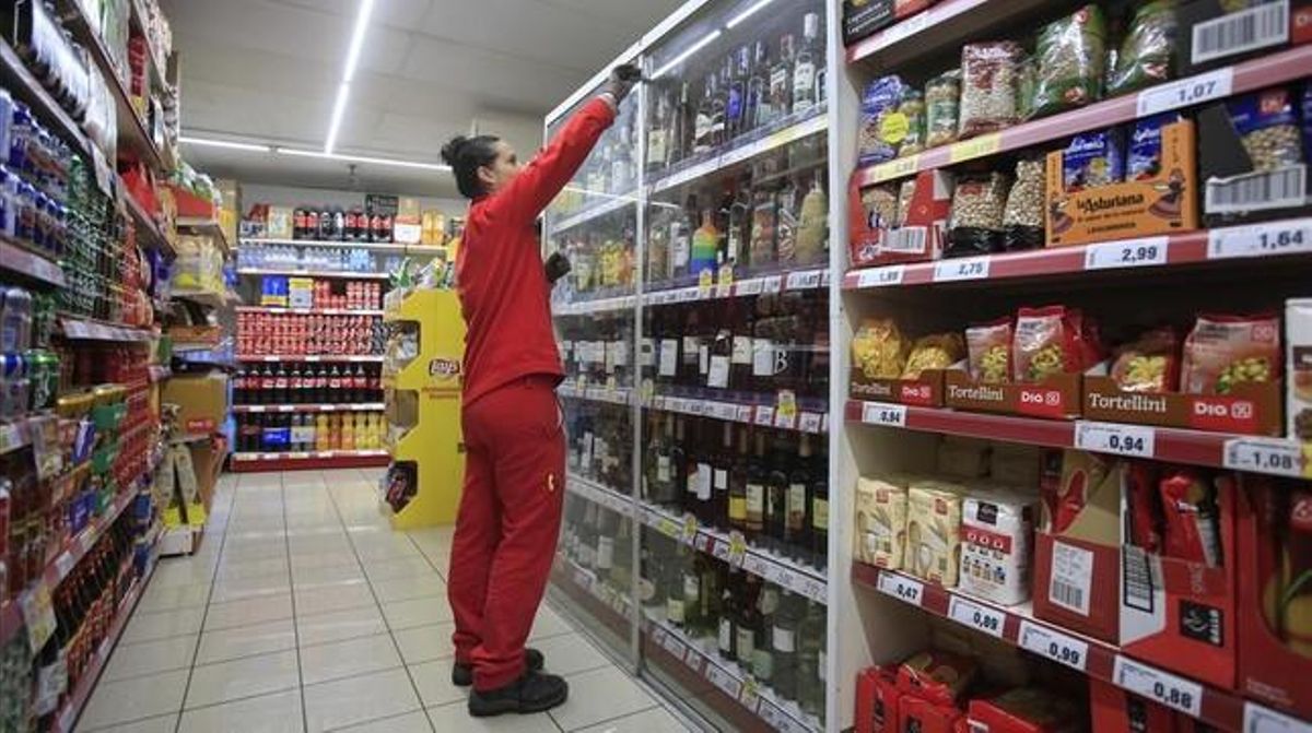 Una empleada repone los productos en un supermercado. Una empleada repone los productos en un supermercado.