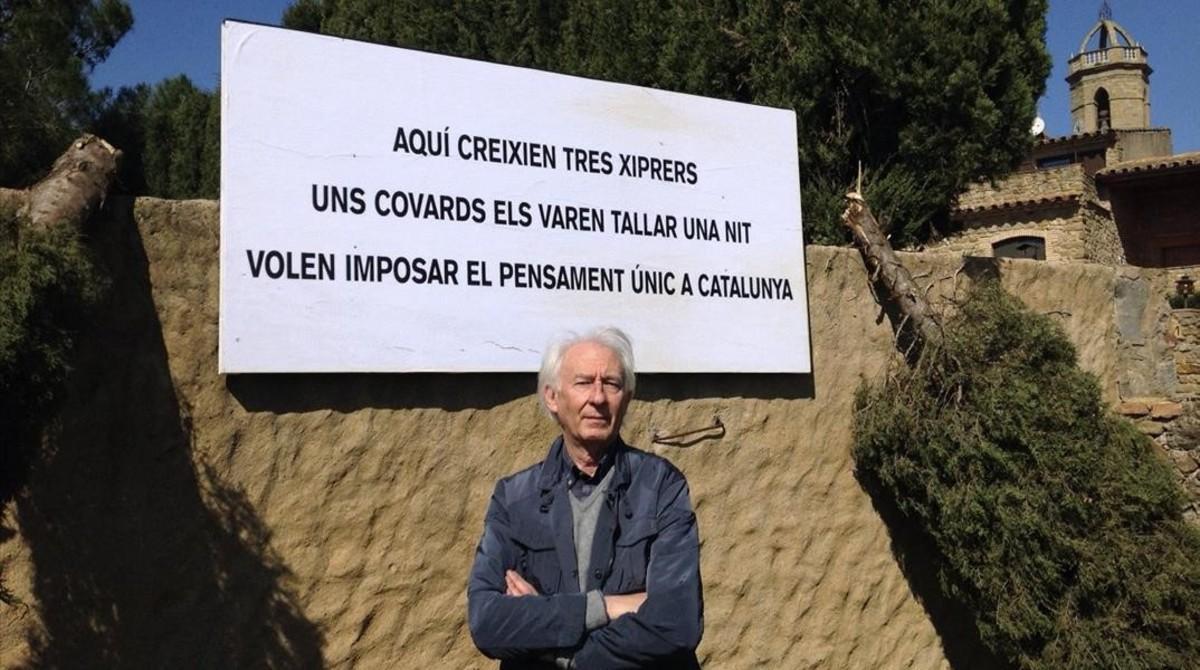 Albert Boadella posa frente a un cartel en el que denuncia los ataques que está sufriendo en su casa del Empordà.
