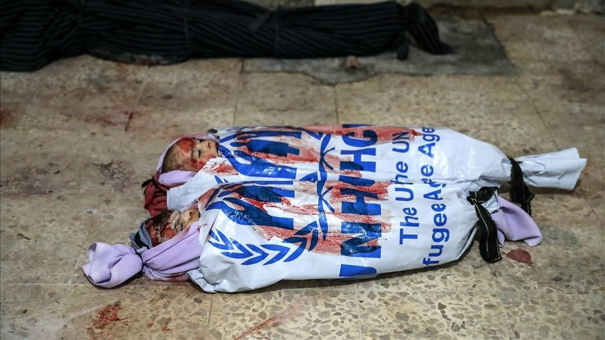 Los cadáveres de dos niños muertos por los bombardeos en Duma yacen envueltos con ropa del ACNUR, la oficina de la ONU para los refugiados. Los cadáveres de dos niños muertos por los bombardeos en Duma yacen envueltos con ropa del ACNUR, la oficina de la ONU para los refugiados.