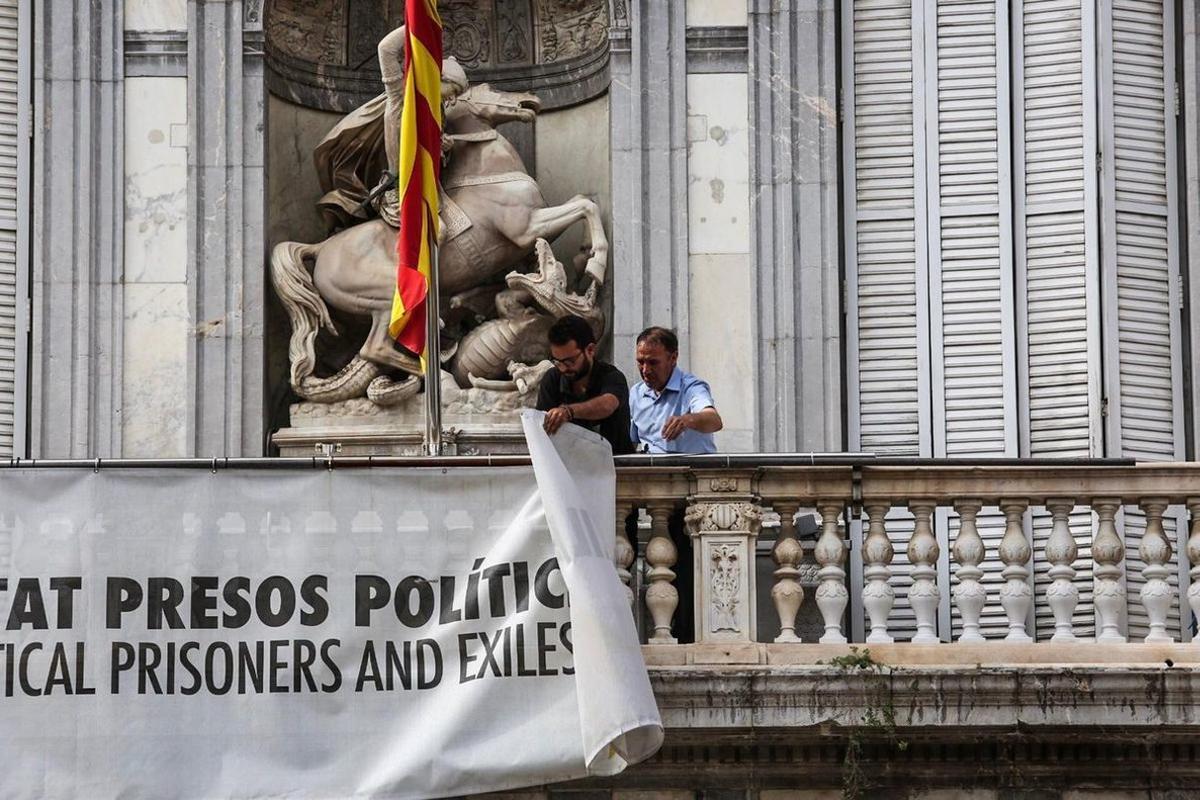 Dos trabajadores de la Generalitat retiran la pancarta que colgaba del Palau, el pasado 27 de septiembre.