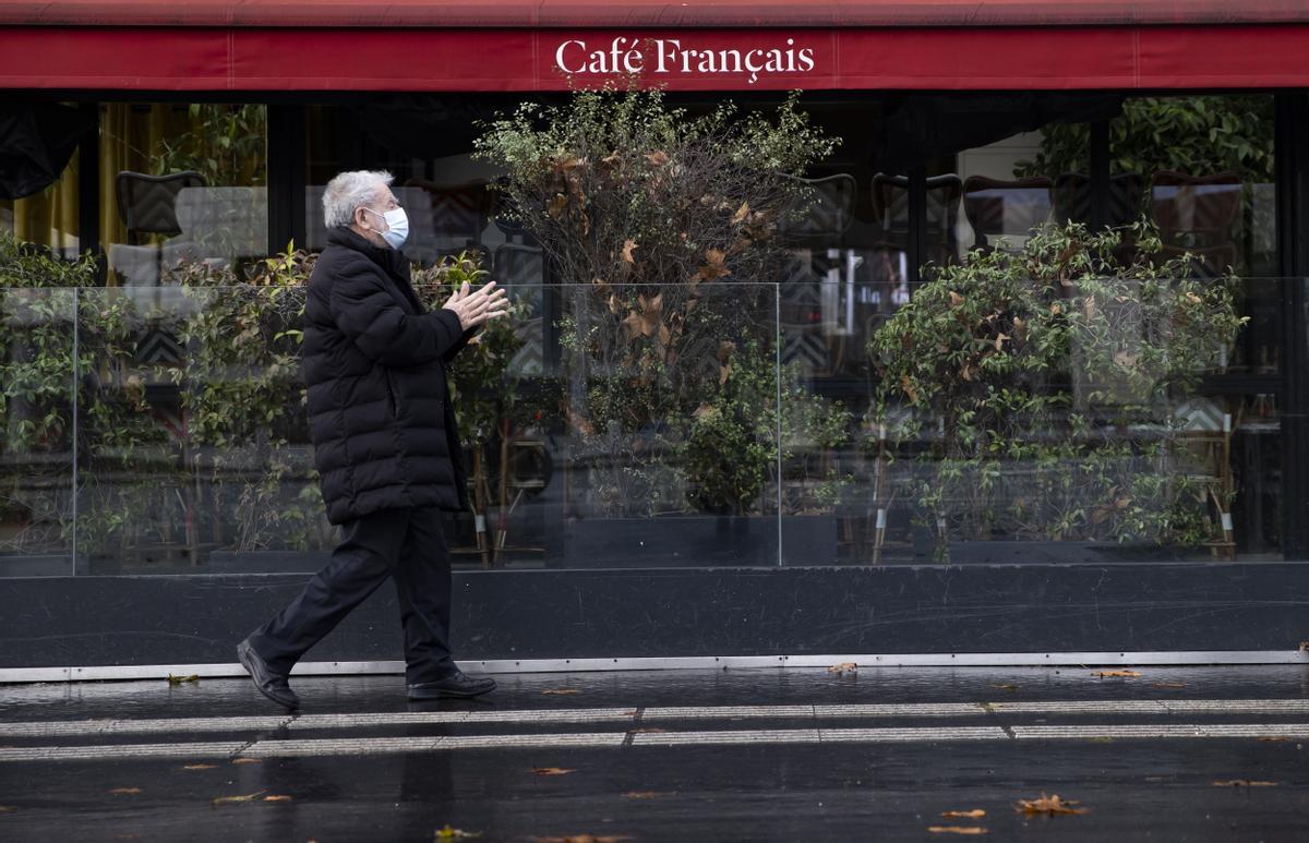 Un parisino camina frente a un café cerrado debido a las restricciones por el coronavirus
