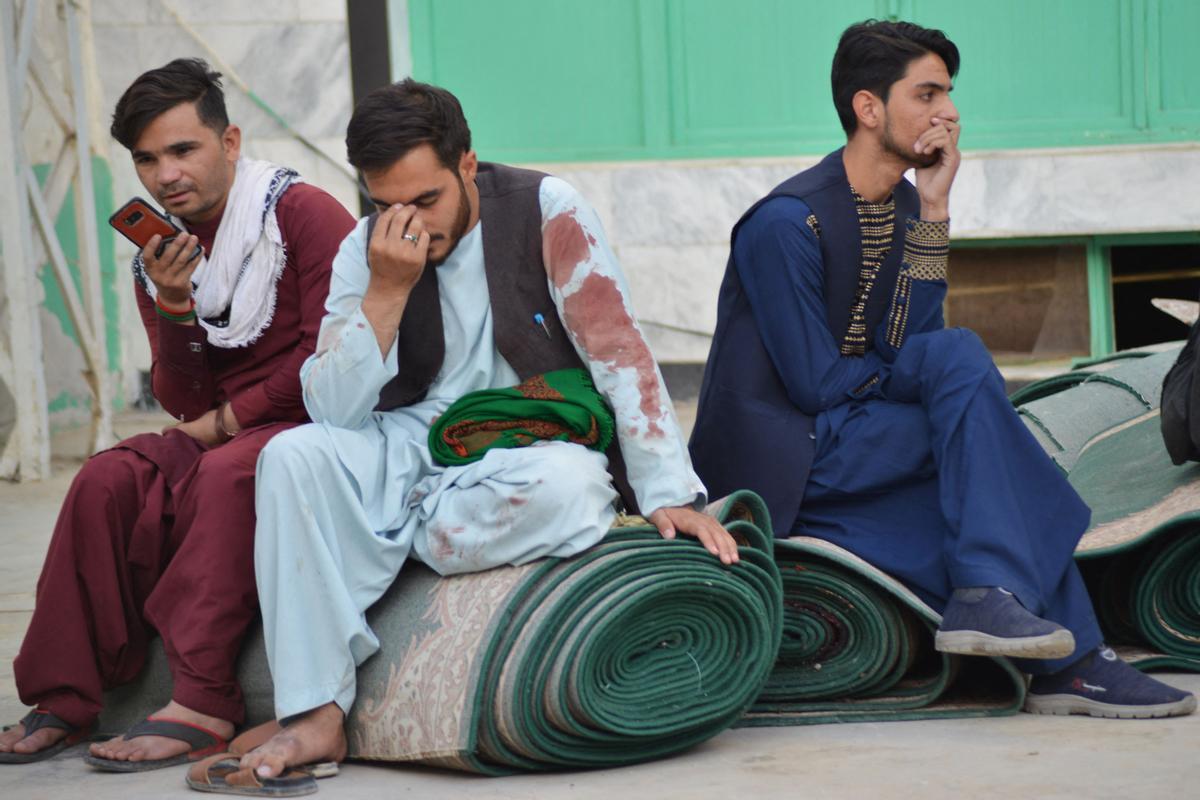 Varios hombres en el exterior de la mezquita chií de Kandahar tras el ataque suicida, este viernes.