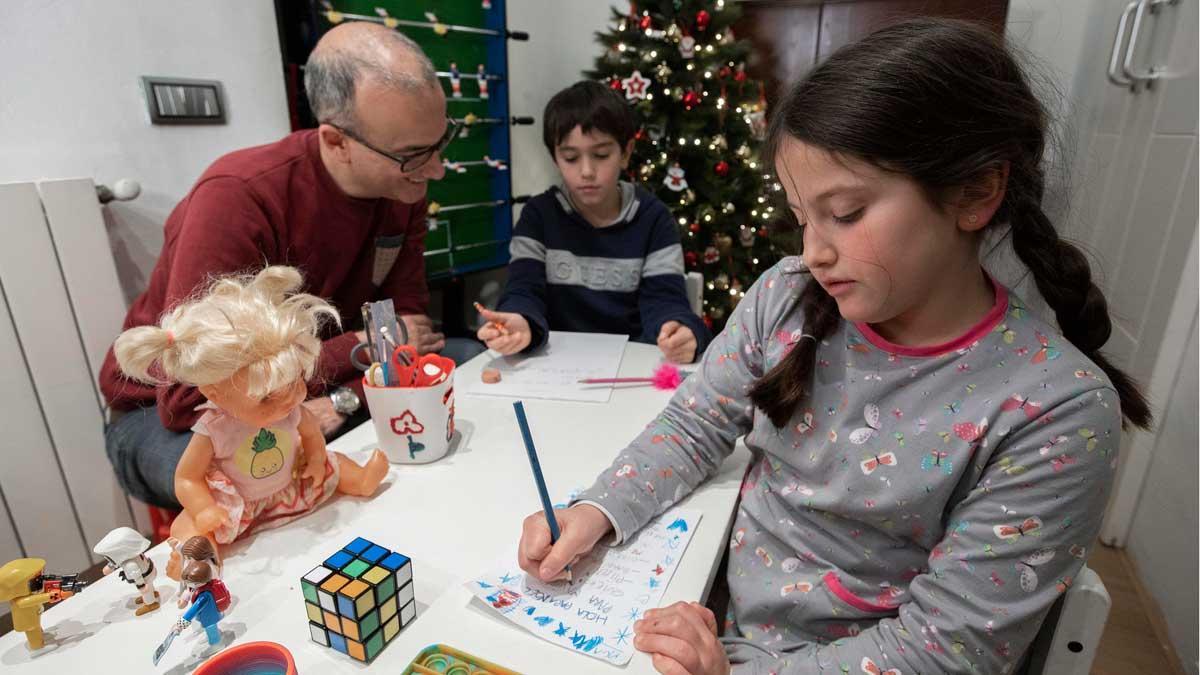 Un padre ayuda a sus hijos a escribir la carta a Papa Noel. 