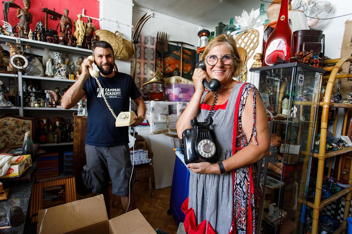 Toni Parra y su madre, Nany, posan con teléfonos ’vintage’ en los Encants de Granollers. Esta es su sala de tesoros de segunda mano que recuperan de pisos vaciados y no ponen a la venta.