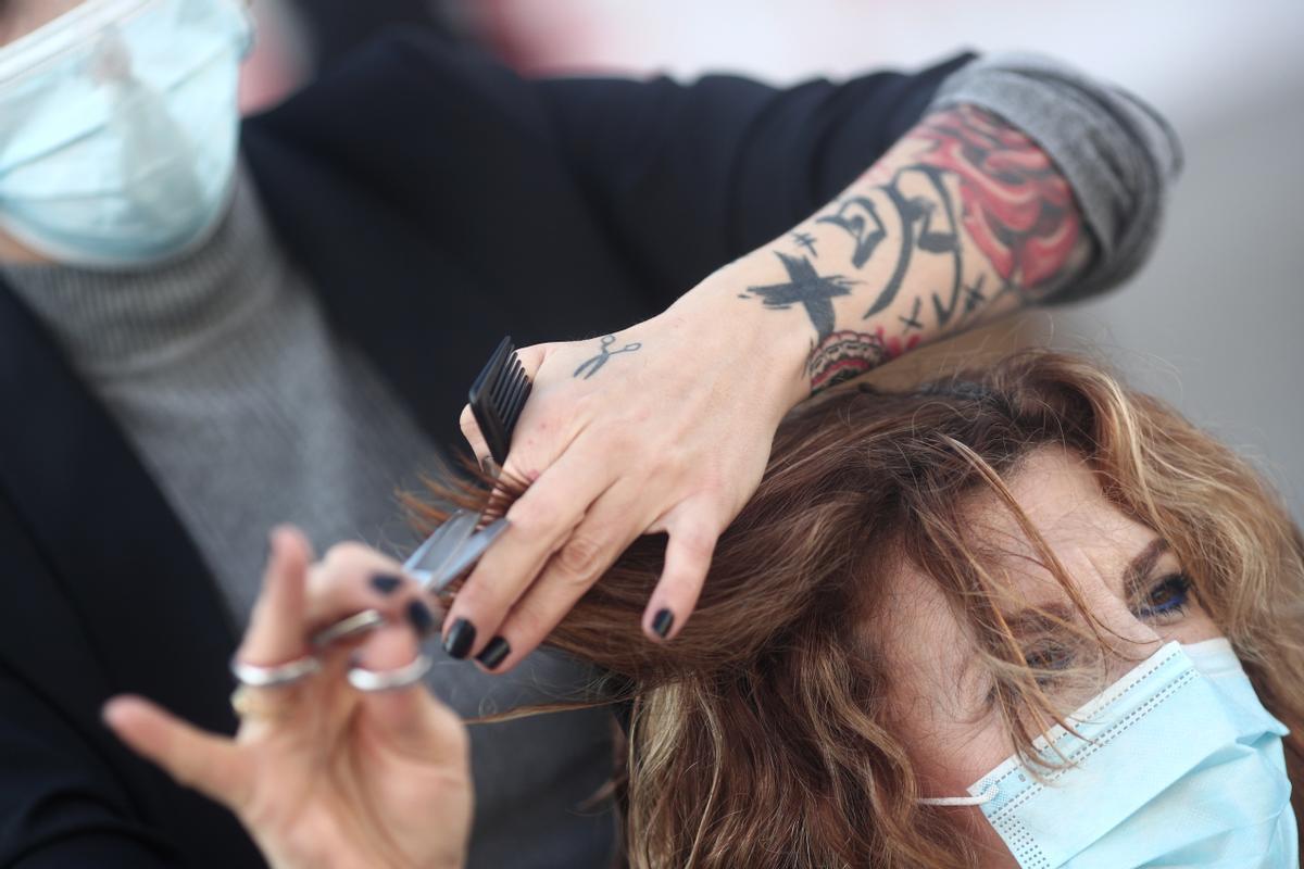 Una peluquera corta el pelo a una mujer. Una peluquera corta el pelo a una mujer.