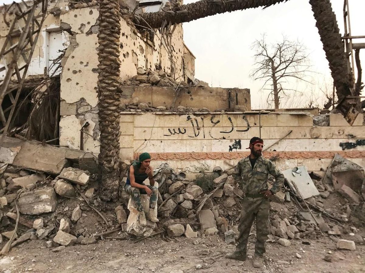Militares del Ejército sirio enfrente de un edificio destrozado en un distrito de Deir Ezzor. Imagen del 5 de noviembre de 2015. Militares del Ejército sirio enfrente de un edificio destrozado en un distrito de Deir Ezzor. Imagen del 5 de noviembre de 2015.