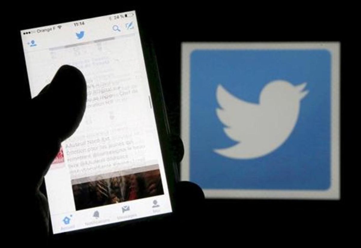 Un usuario de Twitter lee mensajes de esta red social en el móvil frente al logo del pájaro, símbolo de la misma. Un usuario de Twitter lee mensajes de esta red social en el móvil frente al logo del pájaro, símbolo de la misma.