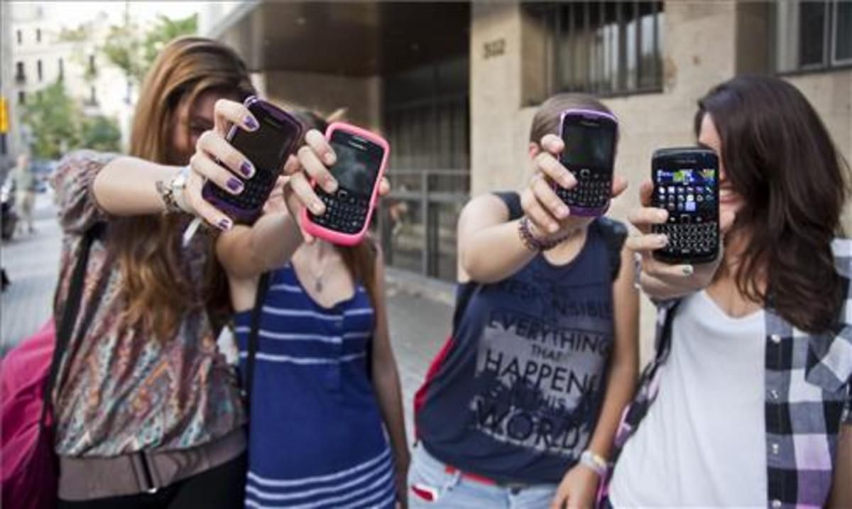 Unas adolescentes muestran sus teléfonos móviles a la puerta de su instituto en Barcelona. Unas adolescentes muestran sus teléfonos móviles a la puerta de su instituto en Barcelona.
