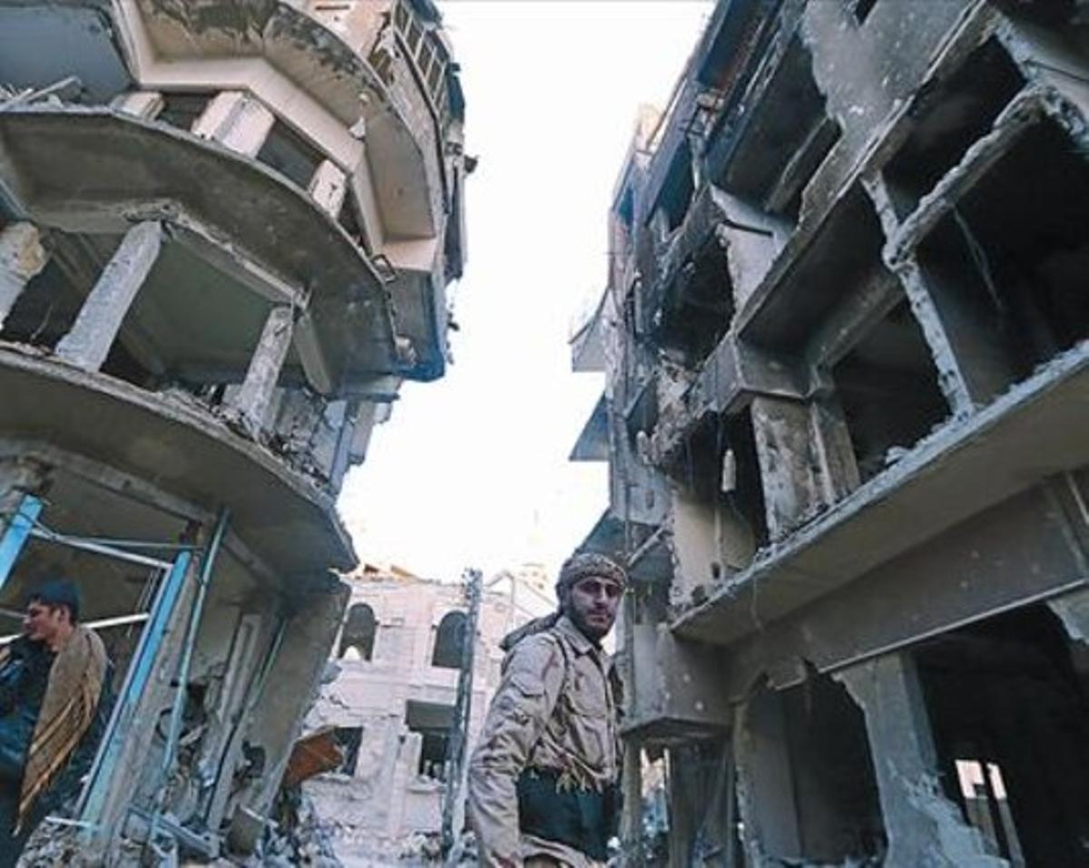 Un combatiente del Ejército Libre Sirio camina entre edificios bombardeados en un barrio de Damasco.