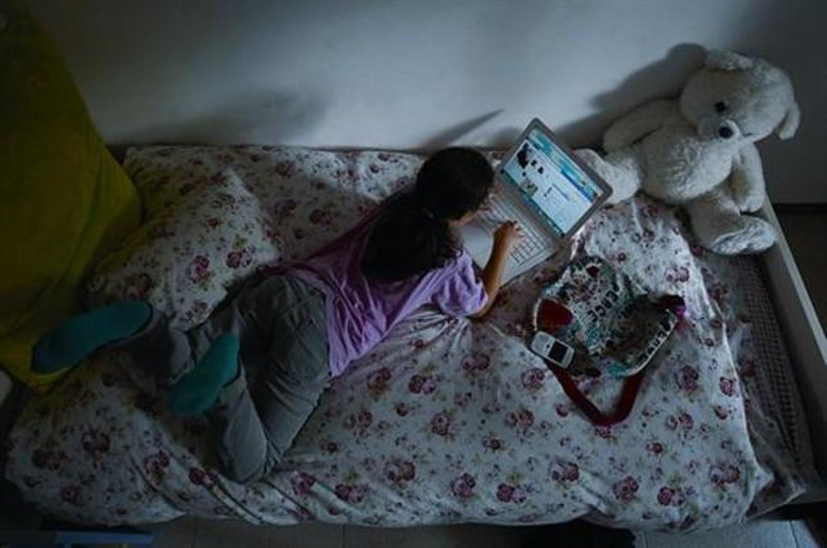 Una menor consulta Facebook mediante un ordenador portátil en su cuarto. Una menor consulta Facebook mediante un ordenador portátil en su cuarto.