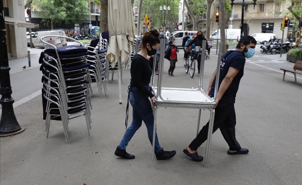 Trabajadores de un restaurante de la rambla del Poblenou, en Barcelona, recogen las mesas de la terraza a las cinco de la tarde. Trabajadores de un restaurante de la rambla del Poblenou, en Barcelona, recogen las mesas de la terraza a las cinco de la tarde.