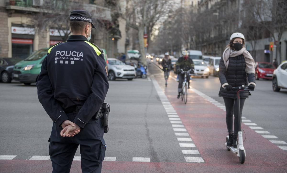 Un agente de la Urbana controla la circulación de bicis y patinetes, en enero de 2021, durante una de las primeras campañas de control de ambos colectivos en Barcelona