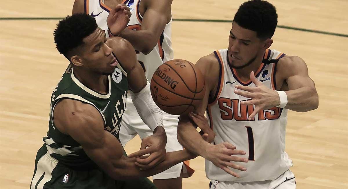 Antetokounmpo (izda.), pelea por una pelota con Booker. Antetokounmpo (izda.), pelea por una pelota con Booker.