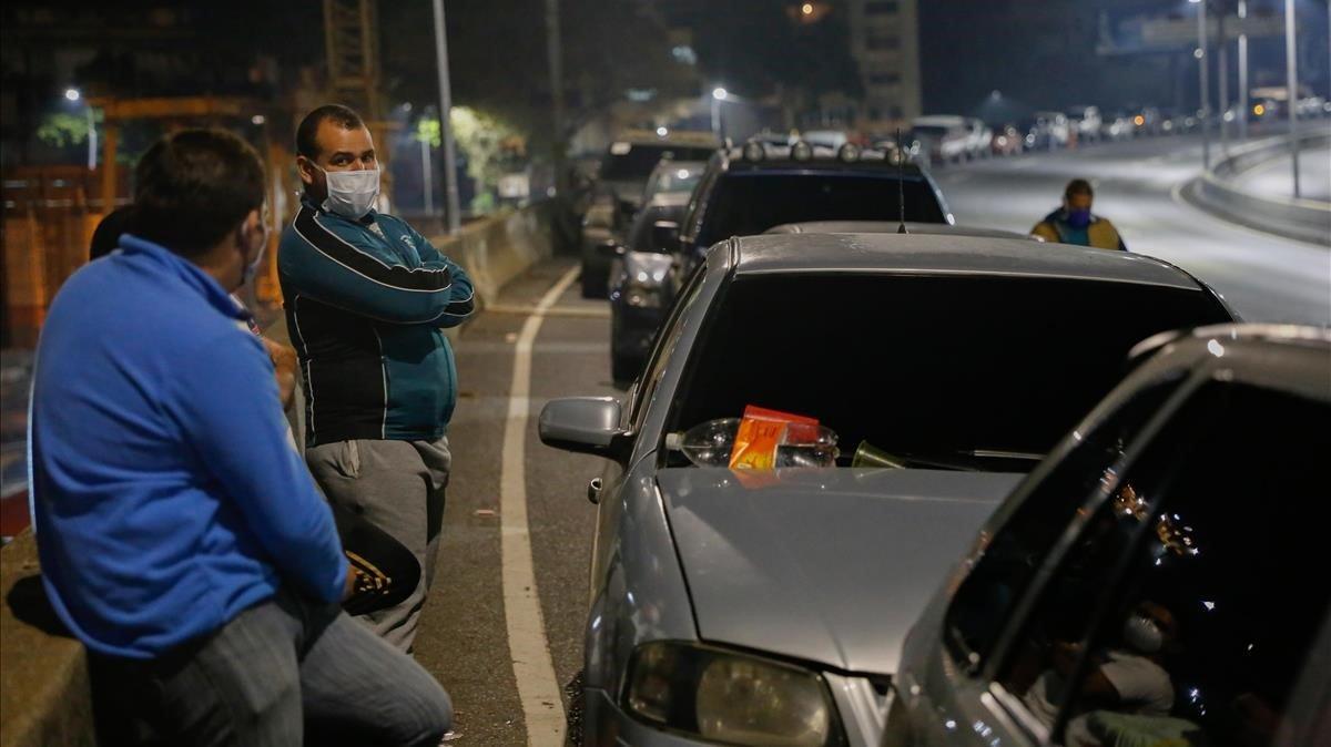 Venezolanos haciendo cola para llenar el depósito de gasolina del coche, el miércoles en Caracas.