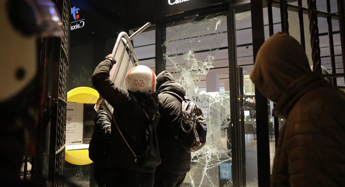 Un grupo de jóvenes ataca una sucursal bancaria durante el segundo día de protestas contra la detención del rapero Pablo Hasél, el 16 de febrero de 2021.