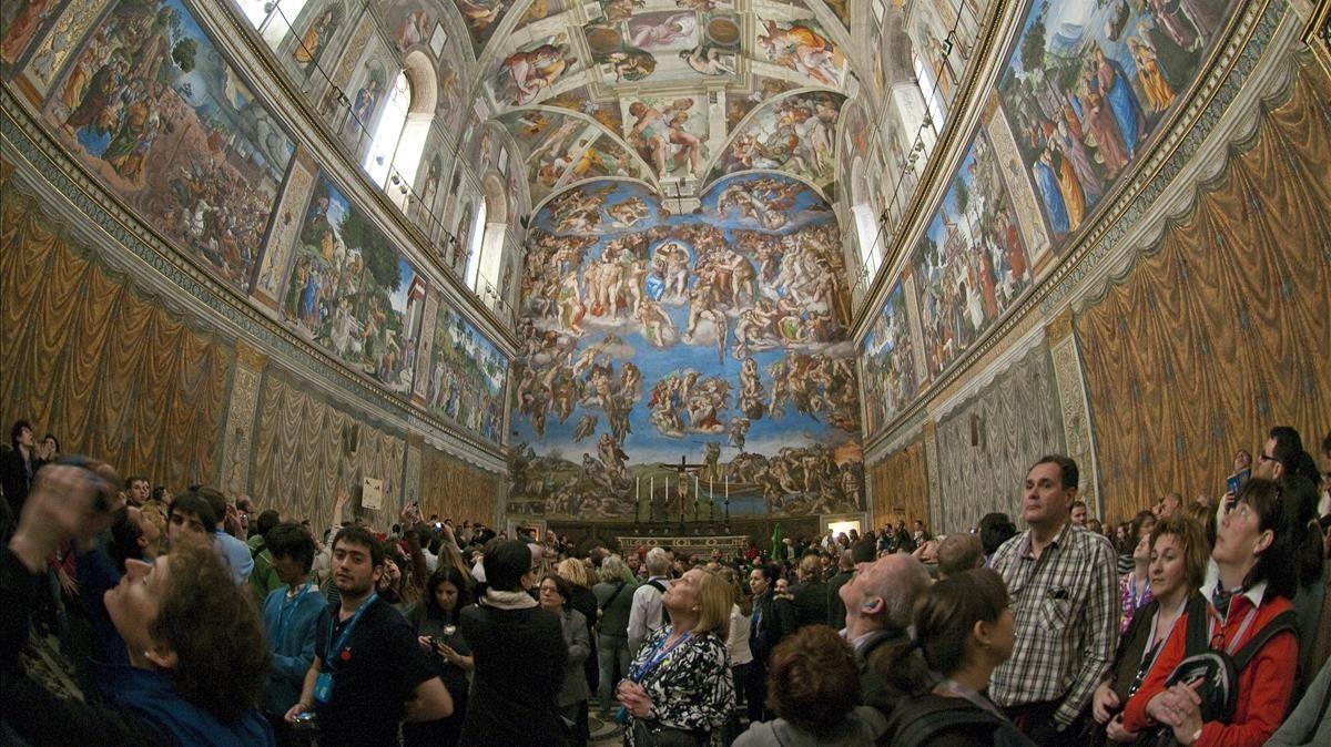 Numerosos turistas observan los frescos de la Capilla Sixtina, en cuya bóveda Miguel Ángel pintó ’La creación de Adán’.