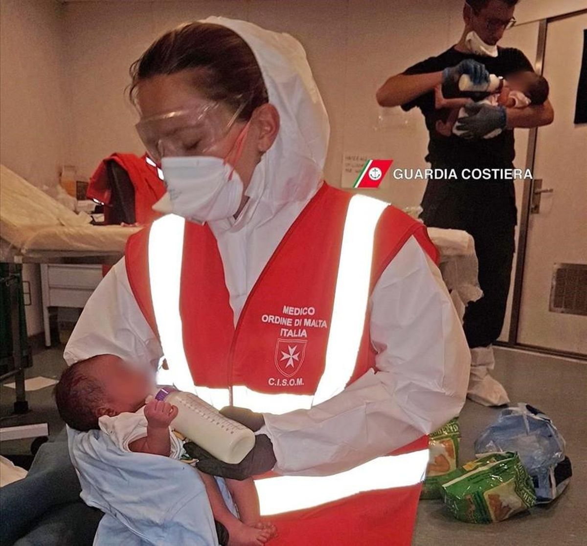 Miembros de la Guardia Costera italiana alimentan a bebés recién nacidos que han sido rescatados ante las costas de Libia. Miembros de la Guardia Costera italiana alimentan a bebés recién nacidos que han sido rescatados ante las costas de Libia.