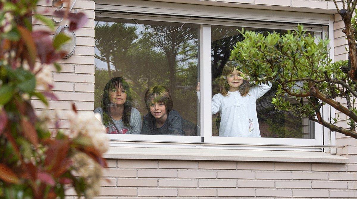 Tres hermanos de Igualada miran por la ventana de su casa durante el confinamiento, el pasado 21 de abril. Tres hermanos de Igualada miran por la ventana de su casa durante el confinamiento, el pasado 21 de abril.