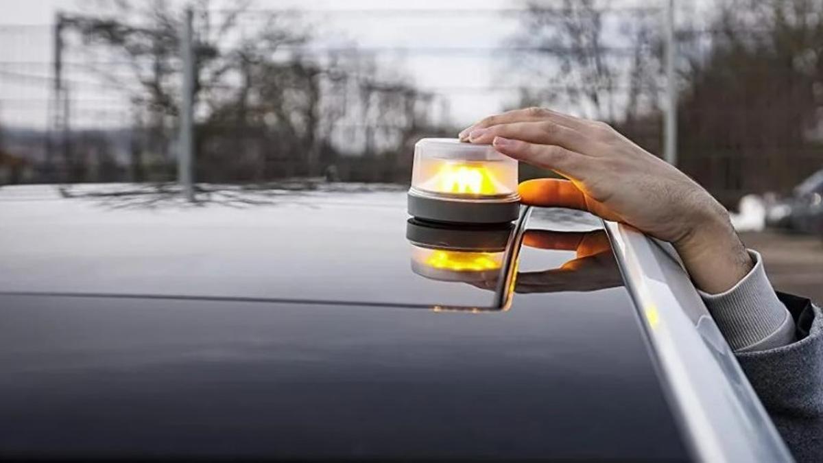 Un hombre coloca un dispositivo de señalización sobre el capó de un coche. Un hombre coloca un dispositivo de señalización sobre el capó de un coche.