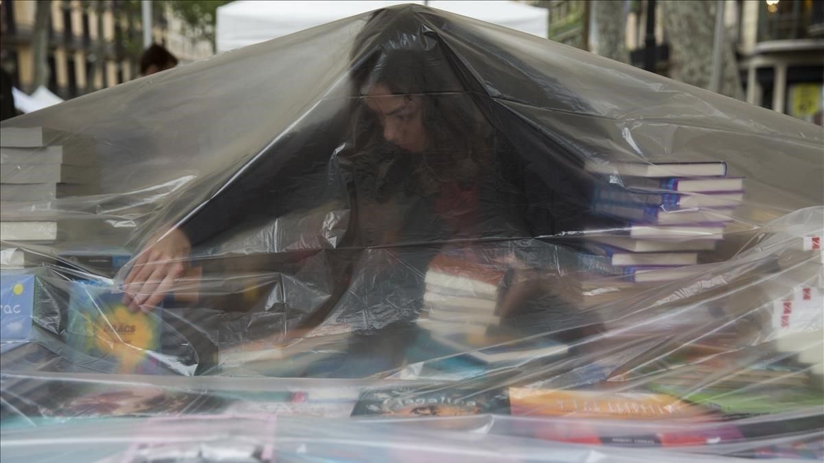Una librera se protege de la lluvia caída a primera hora en Barcelona. Una librera se protege de la lluvia caída a primera hora en Barcelona.