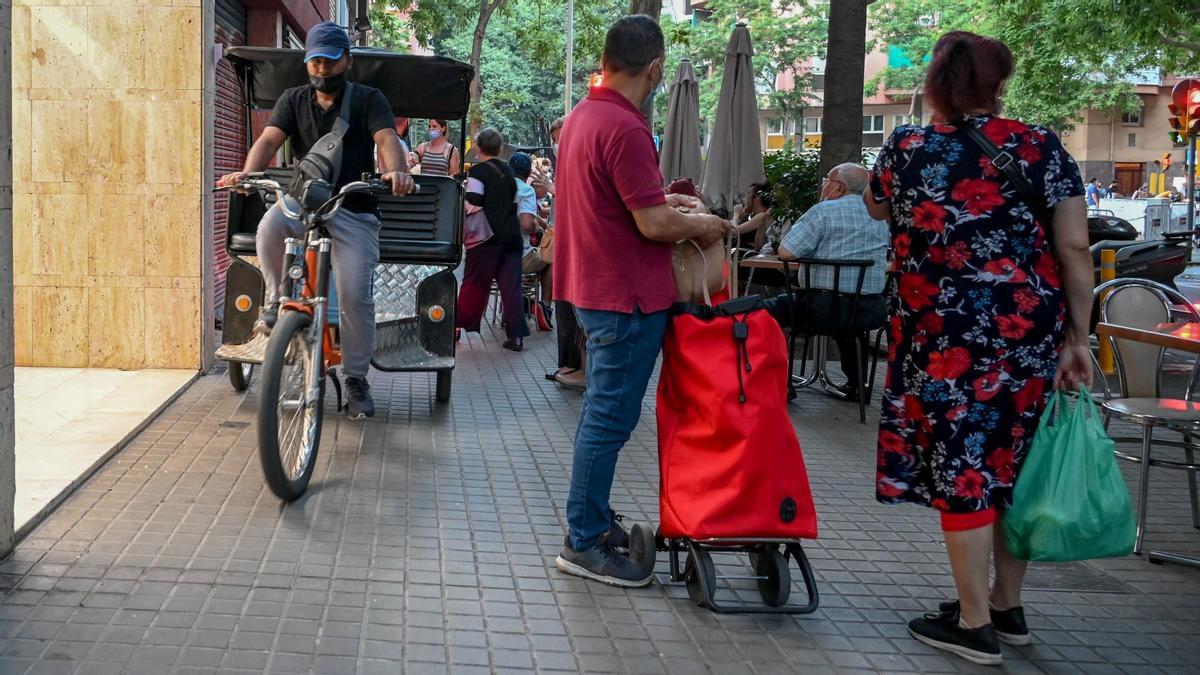 Una bicitaxi trata de abrirse camino entre la estrecha acera con peatones en la calle de Floridablanca en Barcelona, el 23 de junio del año pasado.