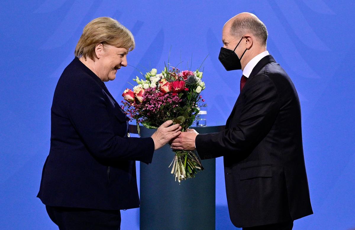 El flamante canciller alemán, Olaf Scholz, da un ramo de flores a su predecesora Angela Merkel en el acto de posesión de hoy en Berlín.