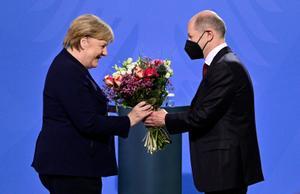 El flamante canciller alemán, Olaf Scholz, da un ramo de flores a su predecesora Angela Merkel en el acto de posesión de hoy en Berlín.